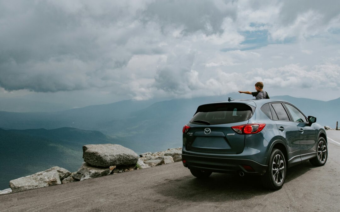 Car parked at a mountain viewpoint with scenic landscape in the background